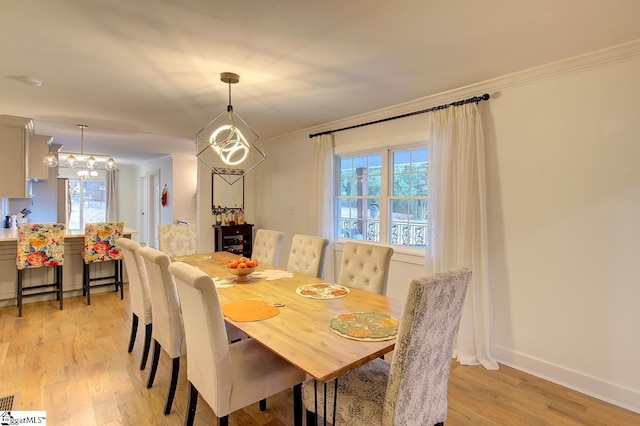 dining room featuring ornamental molding, light wood-type flooring, a chandelier, and baseboards