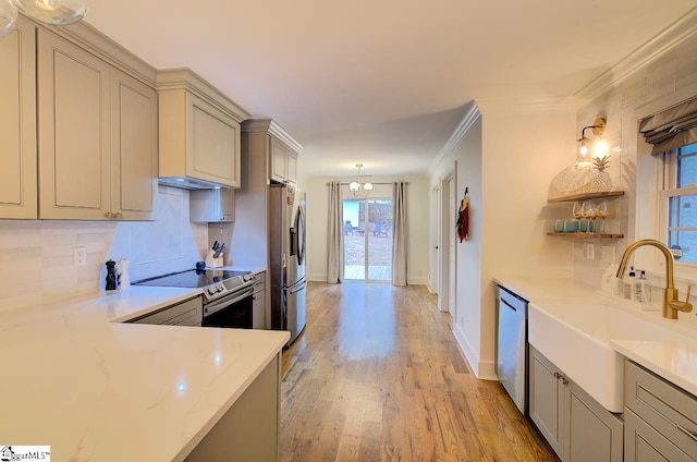 kitchen featuring light wood-style flooring, stainless steel appliances, a sink, tasteful backsplash, and crown molding