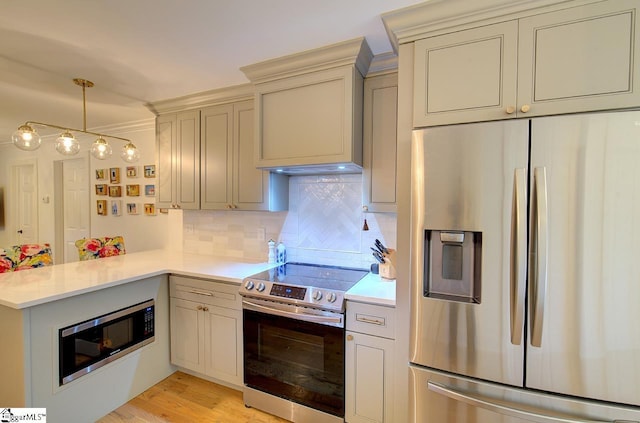 kitchen featuring stainless steel appliances, tasteful backsplash, a peninsula, and light countertops