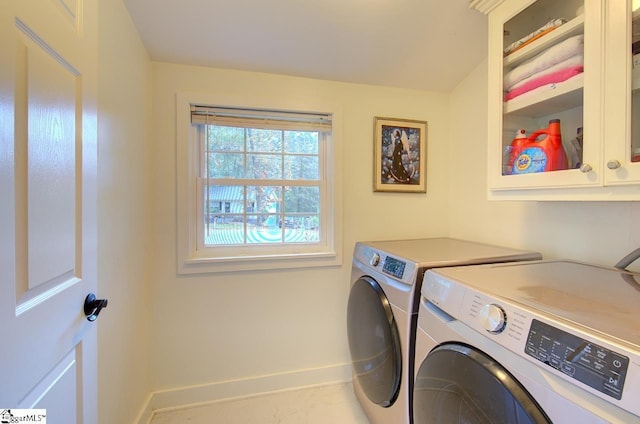 clothes washing area with cabinet space, baseboards, and separate washer and dryer