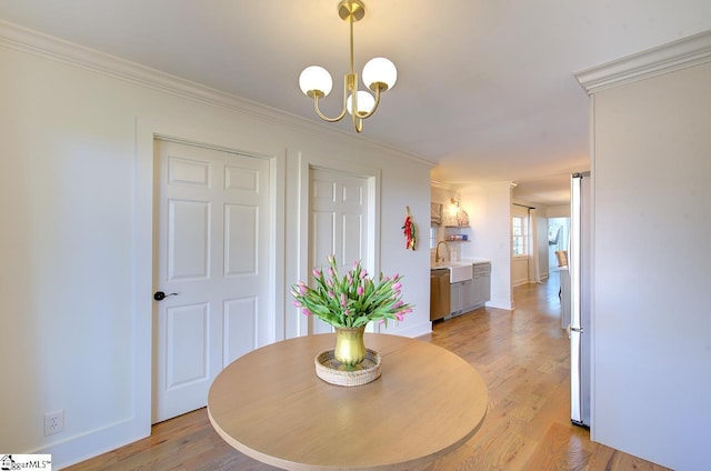 dining area featuring light wood finished floors, baseboards, a chandelier, and crown molding