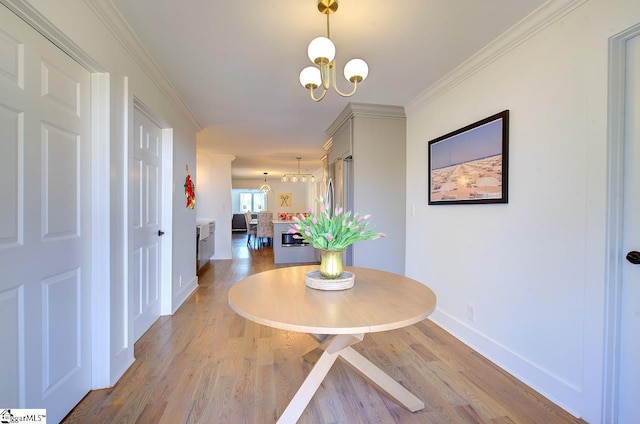 dining space featuring baseboards, ornamental molding, wood finished floors, and an inviting chandelier