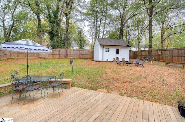 deck featuring a fire pit, outdoor dining space, an outbuilding, and a fenced backyard