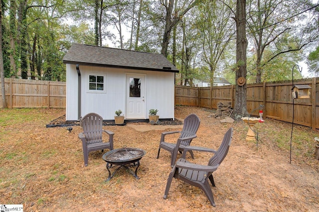 view of yard featuring a fire pit, a storage shed, an outdoor structure, and a fenced backyard