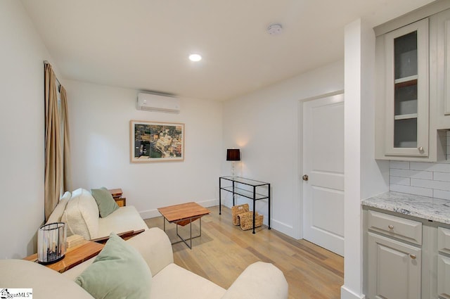 living area with baseboards, a wall mounted AC, recessed lighting, and light wood-style floors