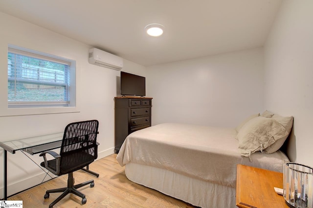 bedroom with baseboards, light wood finished floors, and a wall mounted AC