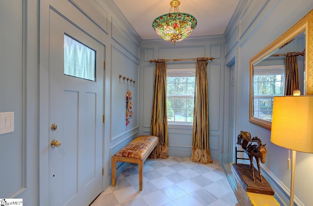 foyer entrance with light floors, ornamental molding, and a decorative wall