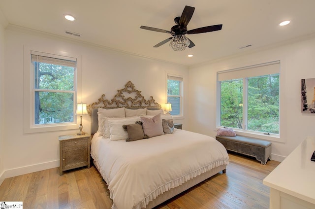 bedroom with light wood-style flooring, visible vents, and ornamental molding