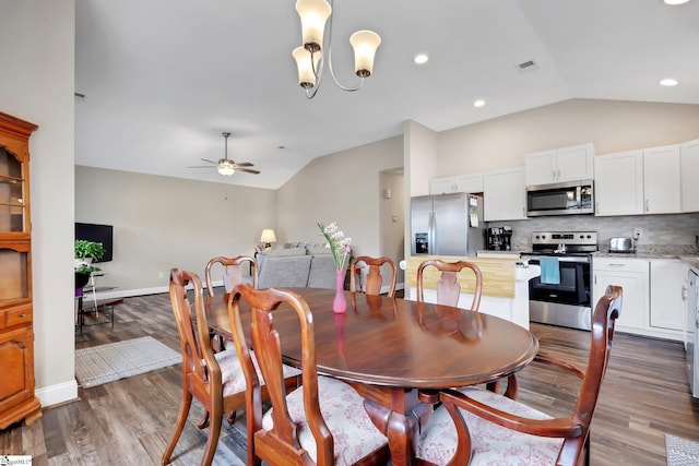 dining room with vaulted ceiling, ceiling fan with notable chandelier, wood finished floors, and visible vents