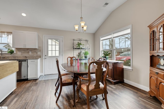 dining area featuring dark wood finished floors, visible vents, an inviting chandelier, vaulted ceiling, and baseboards