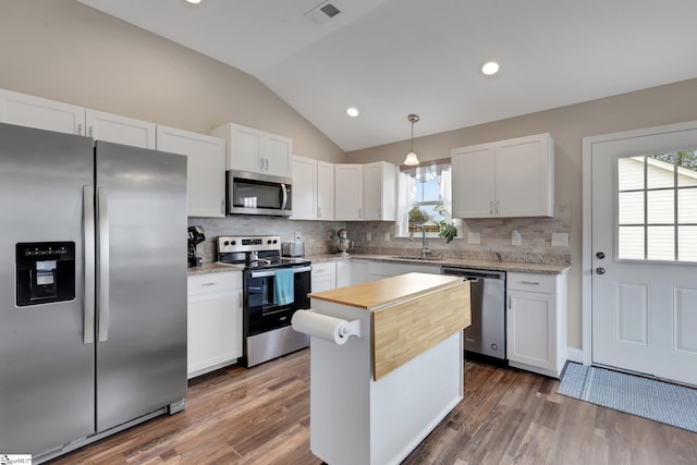 kitchen featuring stainless steel appliances, lofted ceiling, visible vents, white cabinets, and a sink