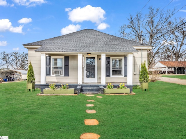 bungalow with a shingled roof, cooling unit, a carport, and a front lawn