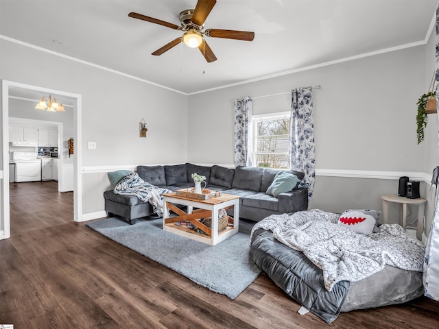 living area with ornamental molding, dark wood-style flooring, washing machine and clothes dryer, and ceiling fan with notable chandelier