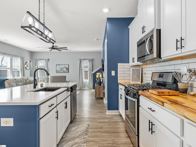 kitchen with open floor plan, appliances with stainless steel finishes, a sink, and butcher block counters