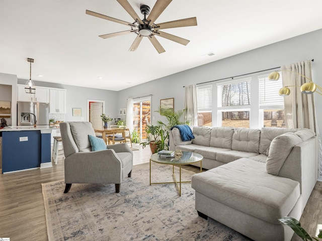 living area with light wood-style flooring, visible vents, and a ceiling fan
