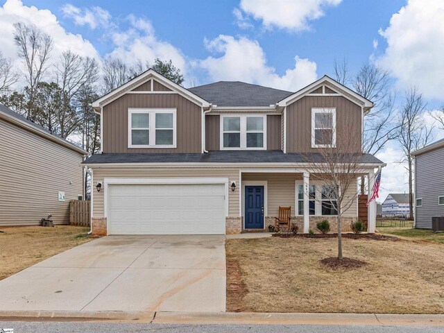 craftsman-style home featuring concrete driveway, an attached garage, covered porch, board and batten siding, and brick siding