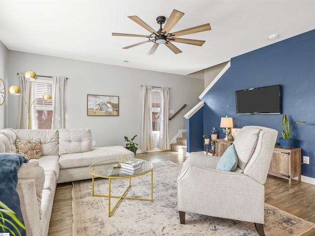 living room featuring a ceiling fan, visible vents, stairway, and wood finished floors