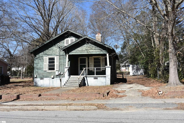 view of front of property featuring crawl space, a chimney, and a porch