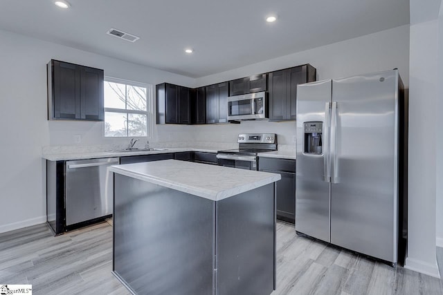 kitchen with light wood-style flooring, stainless steel appliances, a sink, visible vents, and light countertops