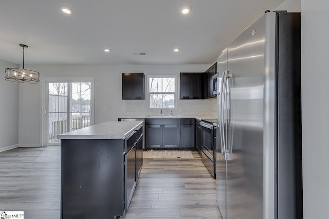 kitchen with a kitchen island, stainless steel appliances, light wood-type flooring, a sink, and recessed lighting