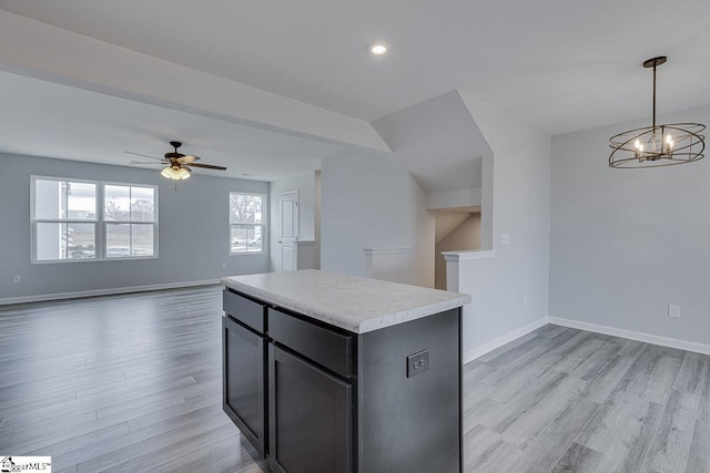 kitchen with light countertops, light wood-type flooring, a kitchen island, and baseboards