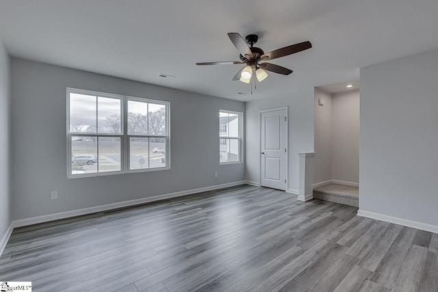 unfurnished room featuring a ceiling fan, visible vents, baseboards, and wood finished floors