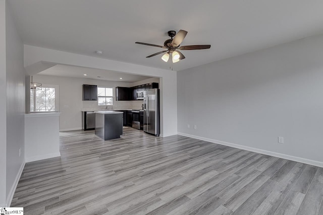 unfurnished living room featuring recessed lighting, light wood-style floors, a sink, ceiling fan, and baseboards