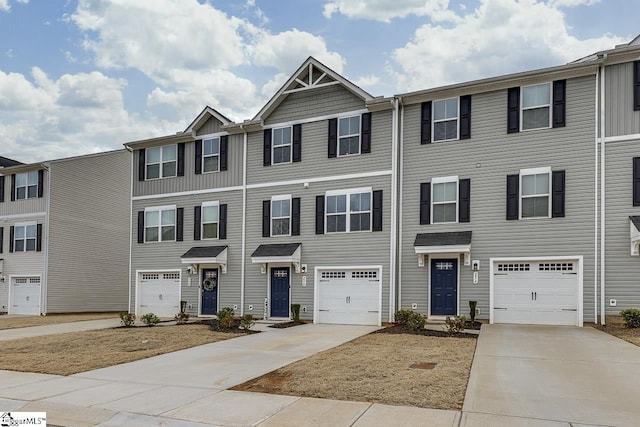 multi unit property featuring a garage and concrete driveway