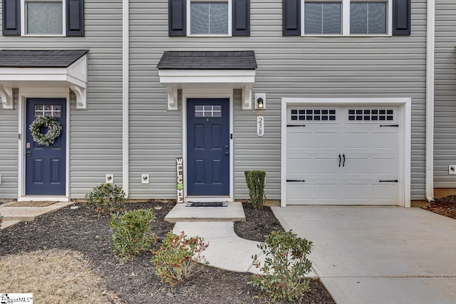 property entrance featuring an attached garage and concrete driveway