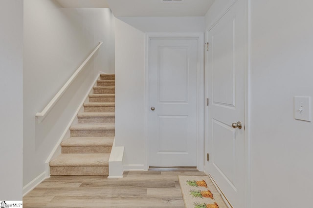 stairway with visible vents, baseboards, and wood finished floors