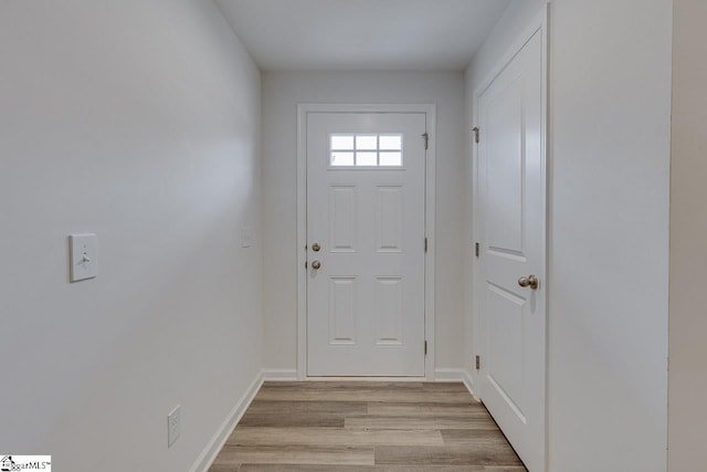 doorway to outside with light wood-type flooring and baseboards