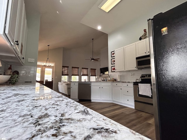 kitchen featuring stainless steel appliances, light stone counters, a peninsula, and white cabinetry