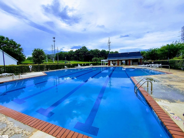 community pool with a patio area and fence