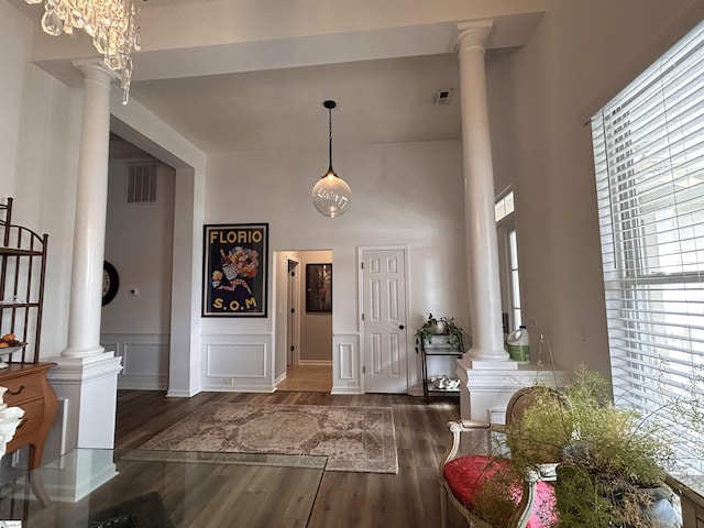 foyer with decorative columns, visible vents, a decorative wall, and wood finished floors