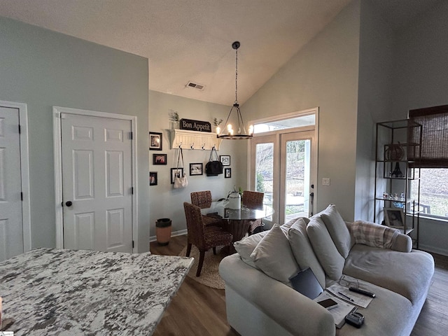 dining area with high vaulted ceiling, dark wood-style flooring, visible vents, and an inviting chandelier