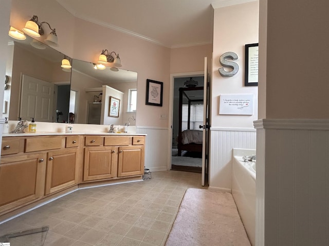 ensuite bathroom featuring a garden tub, a wainscoted wall, double vanity, connected bathroom, and a sink