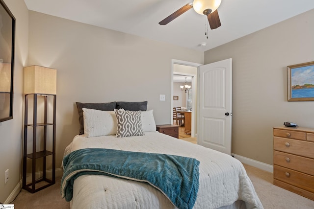 bedroom with carpet flooring, baseboards, and ceiling fan with notable chandelier