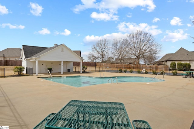 community pool with a patio area and fence