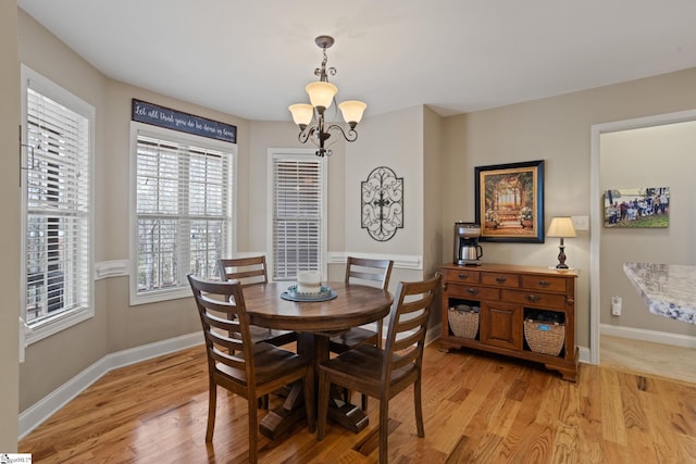 dining space with baseboards, an inviting chandelier, and light wood-style floors