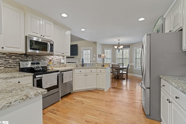 kitchen featuring a peninsula, light wood finished floors, white cabinetry, and appliances with stainless steel finishes