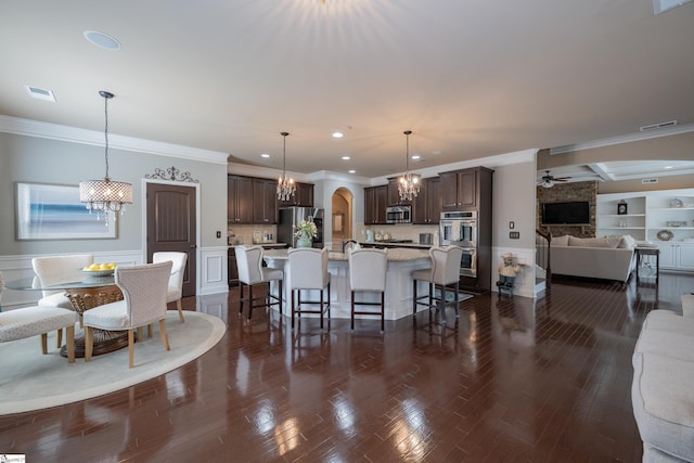 interior space featuring visible vents, open floor plan, stainless steel appliances, dark brown cabinets, and a kitchen bar