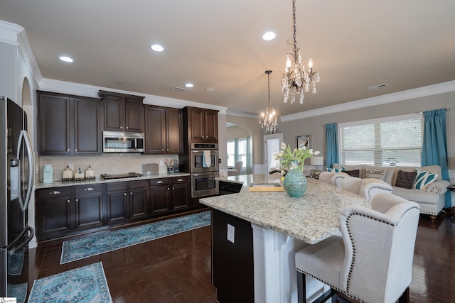 kitchen with dark wood-style floors, arched walkways, a breakfast bar area, appliances with stainless steel finishes, and a chandelier