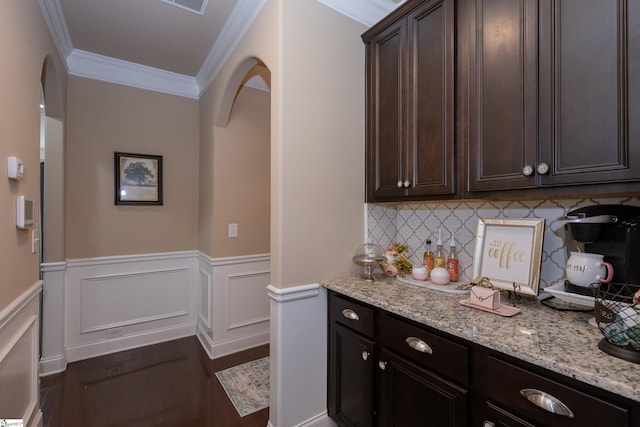 bar featuring arched walkways, a wainscoted wall, dark wood-style flooring, ornamental molding, and tasteful backsplash