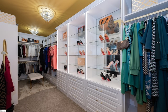 walk in closet with a chandelier and carpet