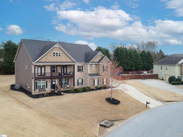 view of front of property featuring driveway, a balcony, and cooling unit