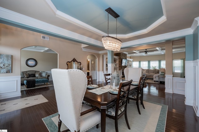 dining area featuring arched walkways, a tray ceiling, visible vents, and a decorative wall