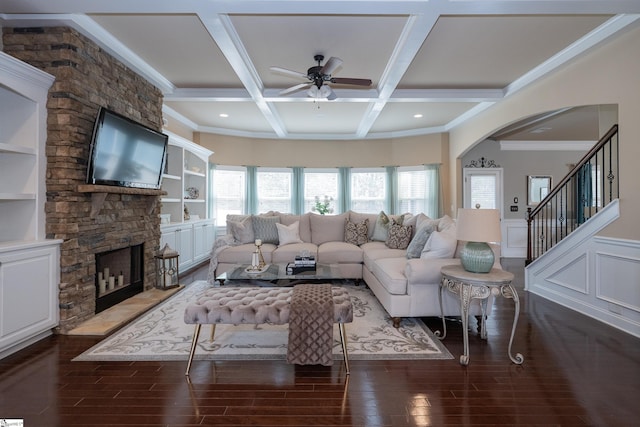 living area featuring coffered ceiling, wood finished floors, beamed ceiling, crown molding, and a fireplace