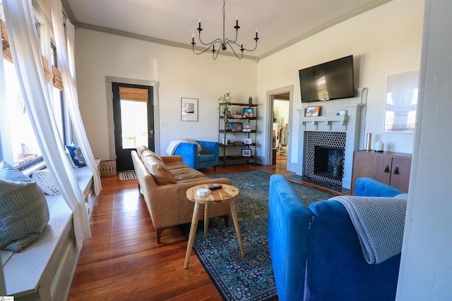 living room with a chandelier, ornamental molding, a fireplace, and wood finished floors