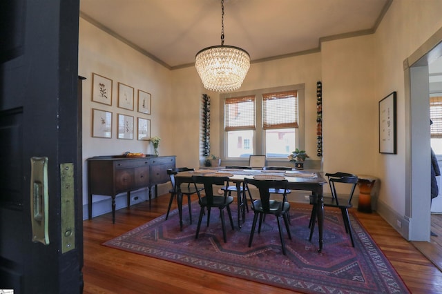 dining area with ornamental molding, a notable chandelier, baseboards, and wood finished floors