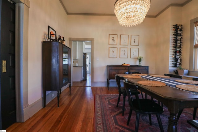 dining room featuring a notable chandelier, baseboards, wood finished floors, and crown molding